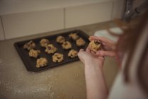 Hands of woman preparing cookies from dough on tray — Stock Photo