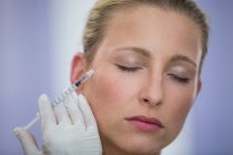 Крупный план средней взрослой пациентки, получающей инъекцию ботокса на лицо — стоковое фото
