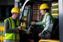 Male worker showing clipboard to female worker in warehouse — Stock Photo