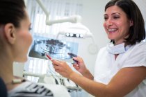 Dentista mostrando radiografía a su paciente en clínica dental - foto de stock