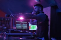 Male dj holding microphone while playing music in bar — Stock Photo
