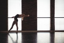 Ballerine pratiquant la danse de ballet à la barre dans le studio de ballet — Photo de stock
