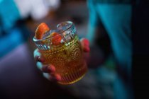 Чоловік тримає стакан апельсинового коктейлю в барі — стокове фото