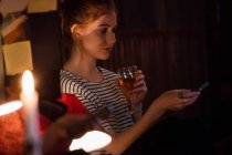 Красивая женщина с помощью мобильного телефона, выпивая вино в баре — стоковое фото