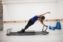 Vue arrière de la femme faisant de l'exercice sur le réformateur dans un studio de fitness — Photo de stock