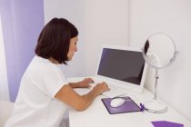 Médico femenino usando PC de escritorio en el escritorio de la clínica - foto de stock