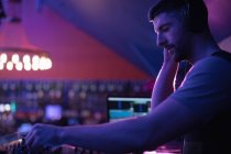 Männlicher DJ hört Kopfhörer, während er in einer Bar Musik abspielt — Stockfoto