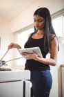 Frau kocht und nutzt digitales Tablet in der Küche — Stockfoto