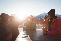 Esquiadores amigos brindar vasos de cerveza en la estación de esquí a la luz del sol - foto de stock