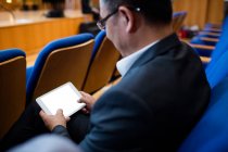 Ejecutivo de negocios participando en una reunión de negocios usando tableta digital en el centro de conferencias - foto de stock