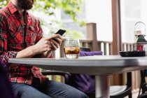 Mid section of man using mobile phone while sitting in bar — Stock Photo