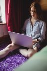 Красива жінка використовує ноутбук у спальні вдома — стокове фото