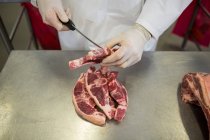 Средняя часть мясника режет мясо на мясокомбинате — стоковое фото