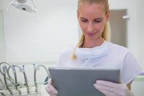 Dentista feminina usando tablet digital na clínica — Fotografia de Stock