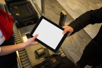 Крупним планом жіночий персонал дає цифровий планшет пасажиру — стокове фото
