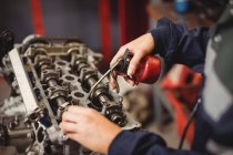 Mid-section of female mechanic oiling car parts in repair garage — Stock Photo