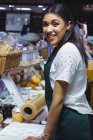 Portrait of smiling waitress standing at counter in cafe — Stock Photo