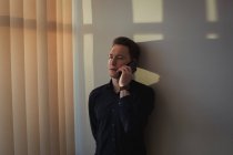 Мужчина-руководитель разговаривает по мобильному телефону в офисе — стоковое фото