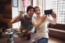 Couple taking selfie while having sushi in restaurant — Stock Photo