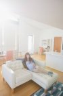 Mujer embarazada pensativo relajarse en el sofá en la sala de estar en casa - foto de stock