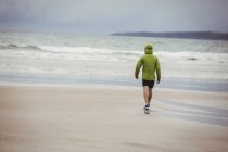 Vista traseira do atleta correndo na praia — Fotografia de Stock