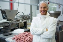 Portrait of male butcher standing with arms crossed at meat factory — Stock Photo