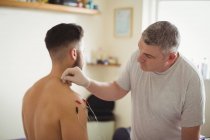 Физиотерапевт проводит электро-сухую иглу на плече пациента-мужчины в клинике — стоковое фото