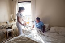 Médecin servant le petit déjeuner au patient âgé dans la chambre — Photo de stock