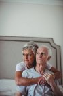 Старша жінка обіймає старшого чоловіка на ліжку в кімнаті ліжка — стокове фото