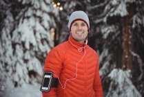 Porträt eines Mannes, der im Winter über Kopfhörer vom Smartphone Musik hört — Stockfoto