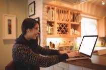 Mulher usando laptop no balcão da cozinha em casa — Fotografia de Stock