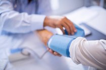 Обрезанное изображение доктора, проверяющего кровяное давление пациента в клинике — стоковое фото