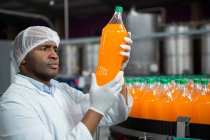 Serious male worker checking products in juice factory — Stock Photo