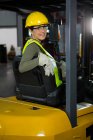 Retrato de mulher trabalhadora que conduz empilhadeira no armazém — Fotografia de Stock