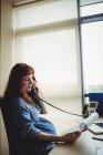 Grávida empresária falando ao telefone enquanto trabalhava no escritório — Fotografia de Stock