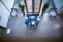 Overhead view of surgeons discussing over medical report in hospital corridor — Stock Photo