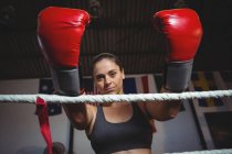 Retrato de boxeador feminino com luvas de boxe no ringue de boxe no estúdio de fitness — Fotografia de Stock