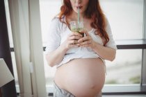 Pregnant woman drinking juice at home — Stock Photo
