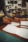 Mid-section of craftswoman arranging leather piece on workbench in workshop — Stock Photo