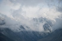 Vistas panorámicas de hermosas montañas cubiertas de nieve y nubes - foto de stock