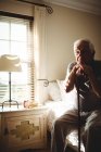 Thoughtful senior man with his walking stick in the bedroom at home — Stock Photo