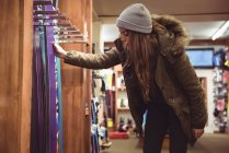 Hermosa mujer seleccionando esquí en una tienda - foto de stock