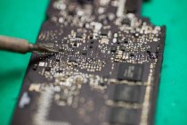 Close-up de microchip sendo fixado em uma placa de circuito usando ferro de solda — Fotografia de Stock