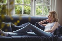 Продумана жінка сидить на дивані у вітальні вдома — стокове фото