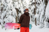 Чоловік стоїть і проведення сноуборді вкриті снігом гори — стокове фото