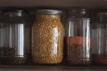 Nahaufnahme verschiedener Linsen und Bohnen in Gläsern im Küchenregal — Stockfoto