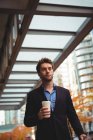 Бизнесмен с одноразовой чашкой кофе и цифровым планшетом во время прогулки по улице — стоковое фото