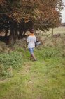 Женщина с корзиной ходит по зеленому полю — стоковое фото