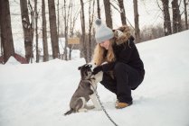 Donna accarezzare giovane cane siberiano durante l'inverno — Foto stock
