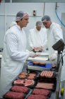 Butchers weighing packages of minced meat at meat factory — Stock Photo